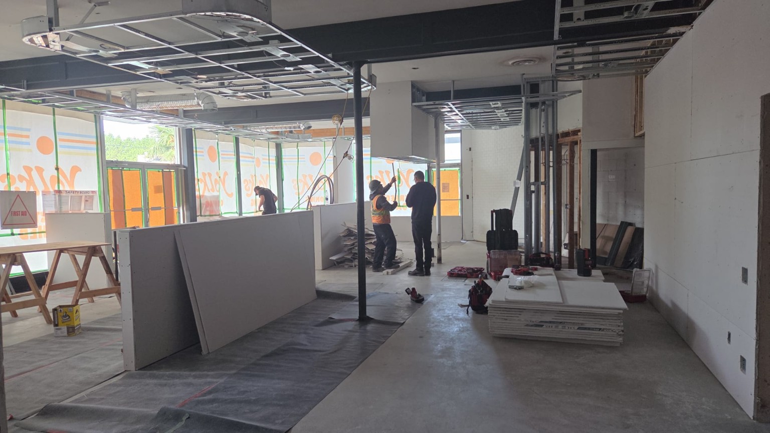 Commercial interior during construction with open ceiling framing and workers