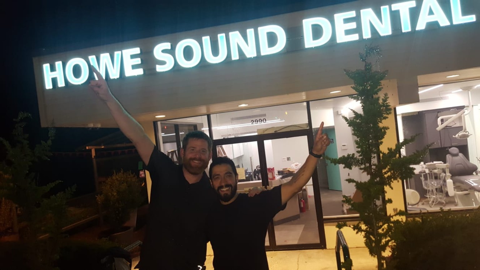 Optus Power team outside the illuminated Howe Sound Dental storefront